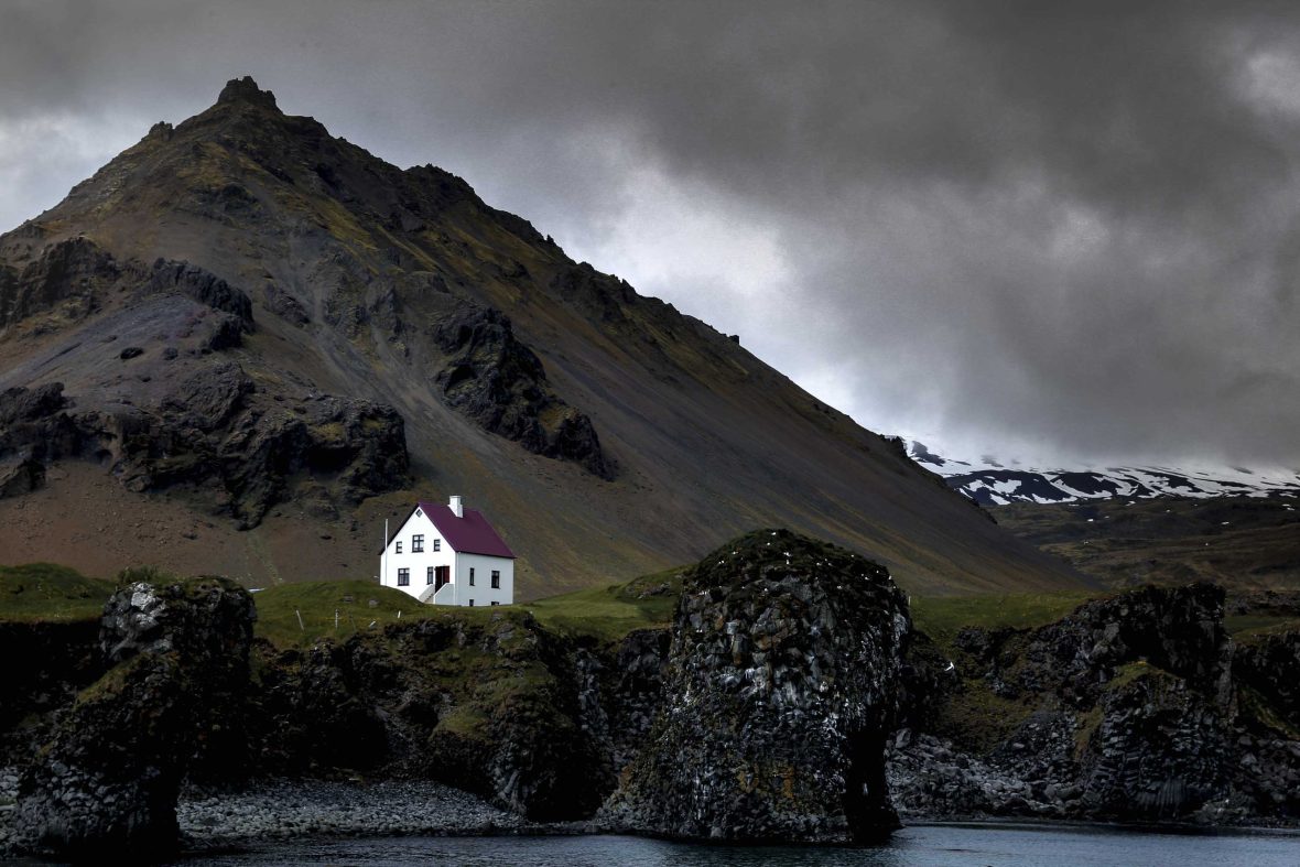 A white house with red roof on some rocks.