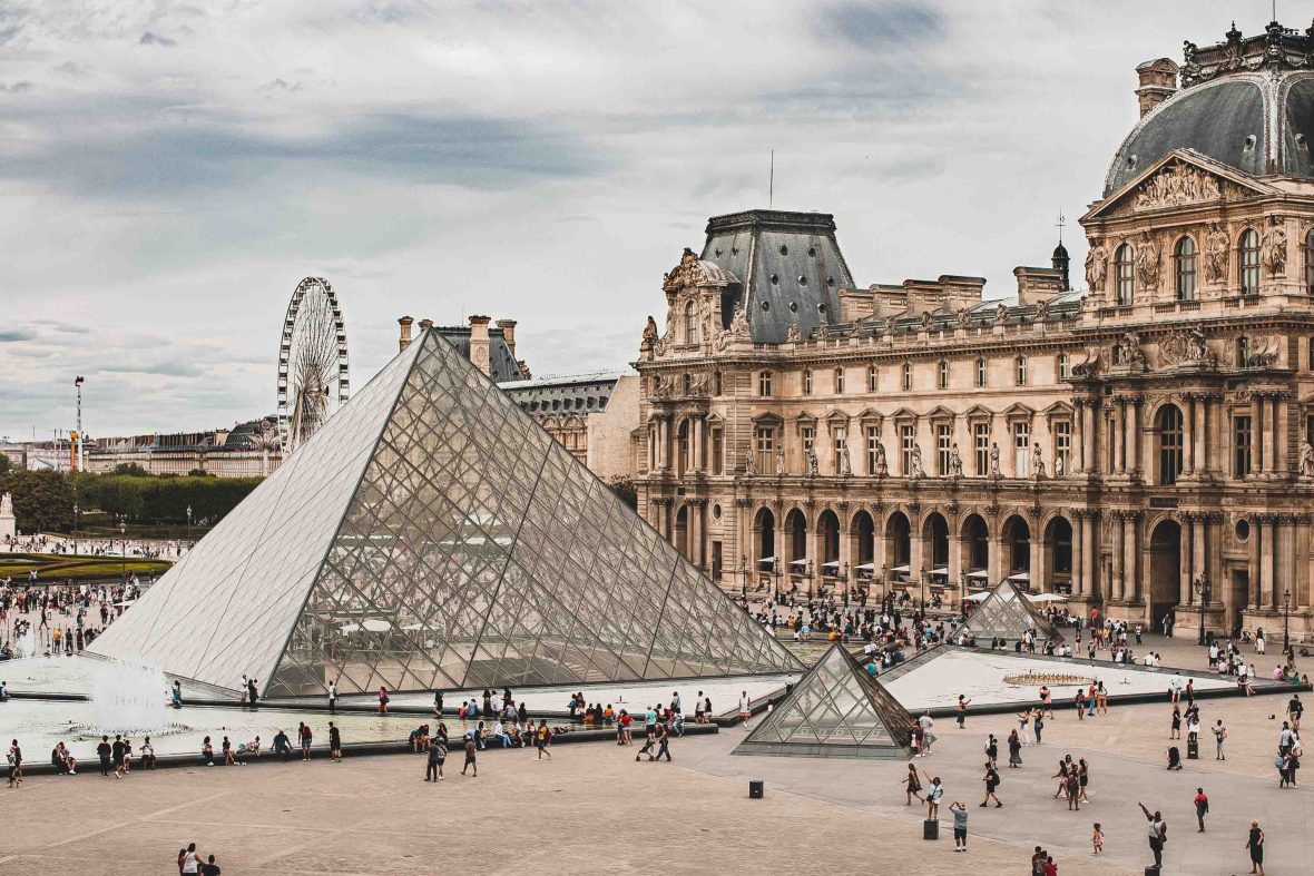 The Lourve with a pyramid structure and lots of people out front.