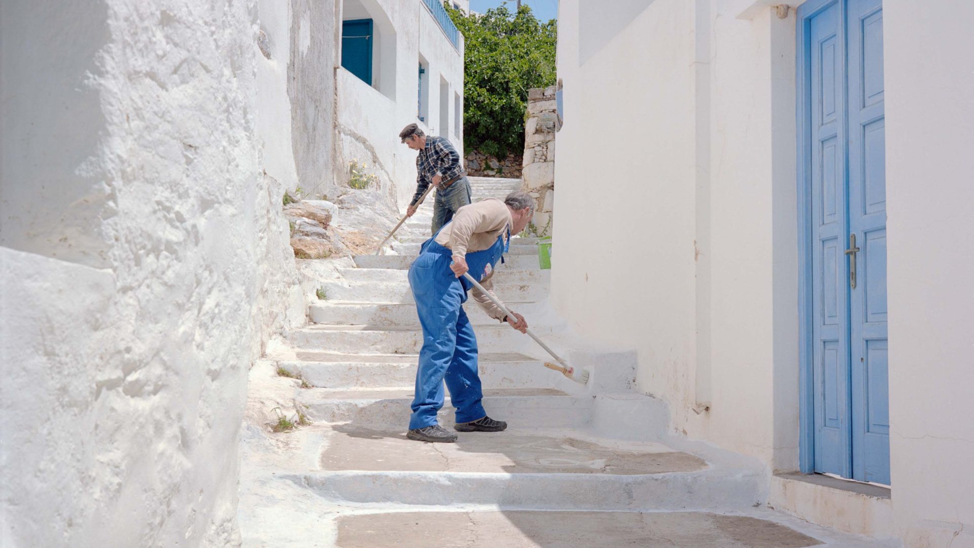 Two men sweep white streets.