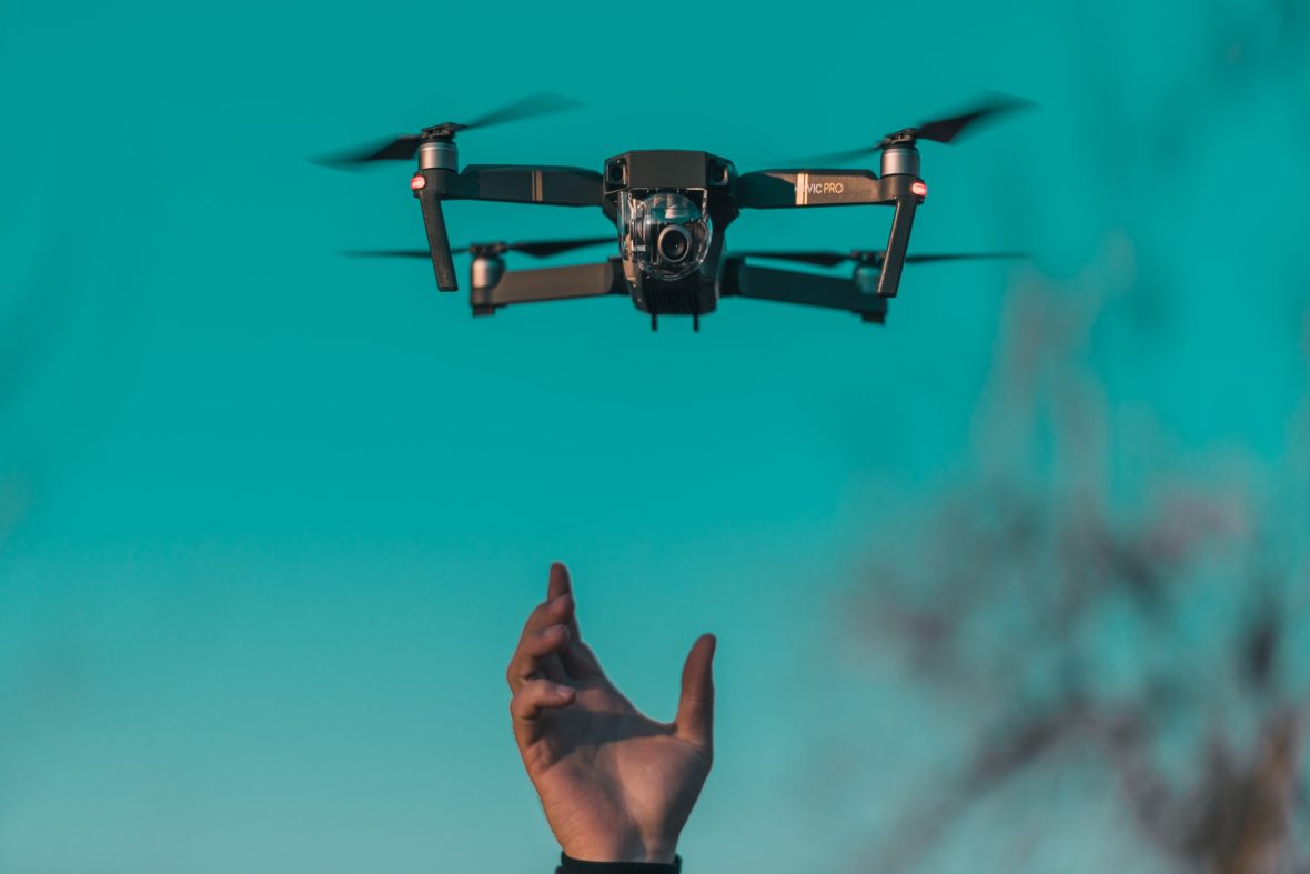 A hand appearing before a drone over a blue sea.