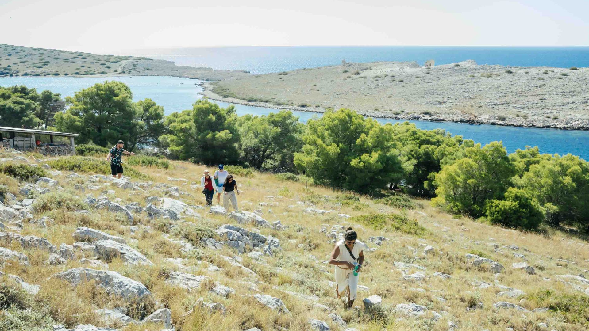 A group of people treks up a dry hillside.